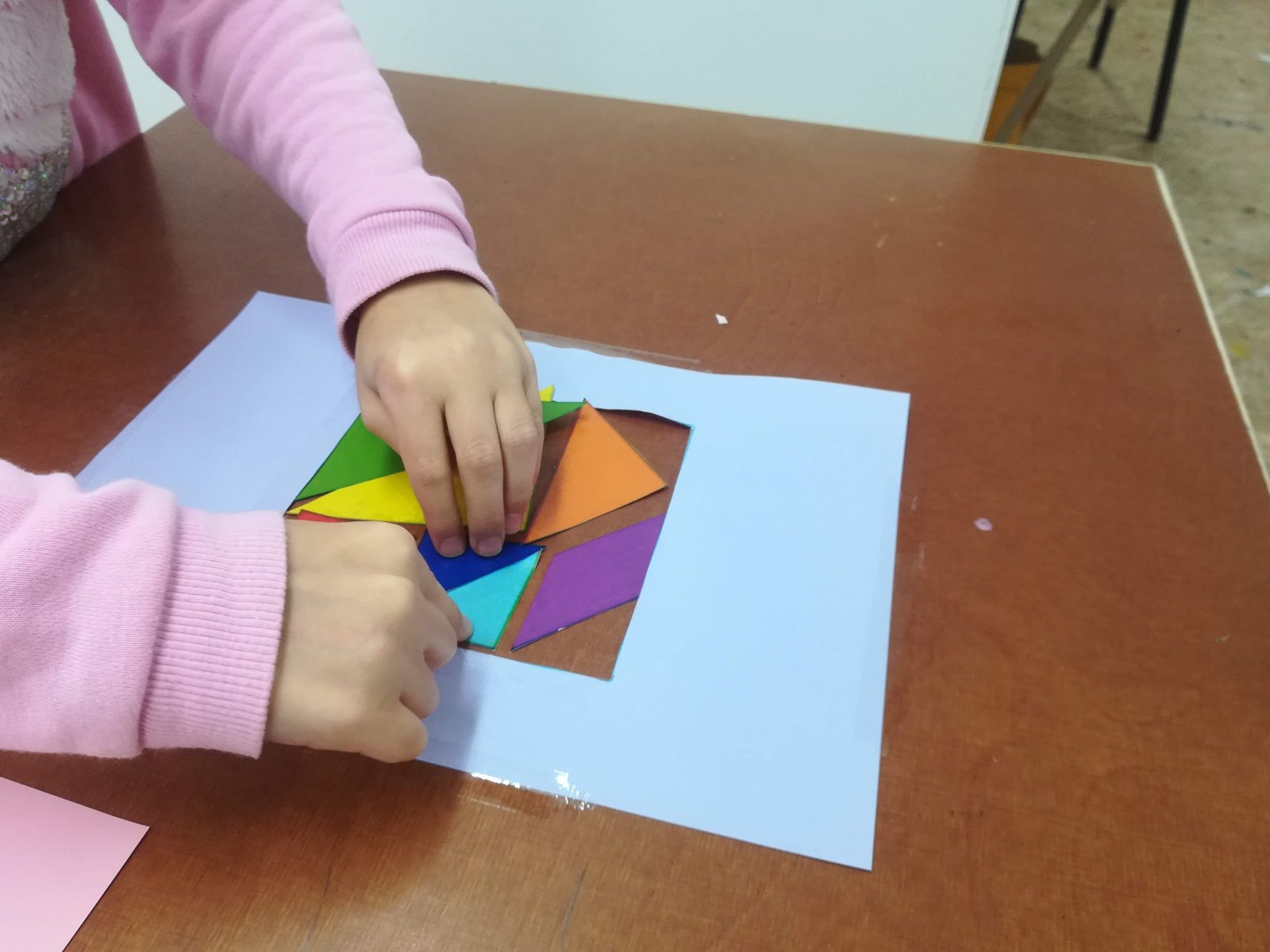 A student's hands arranging coloured shapes during a challenge