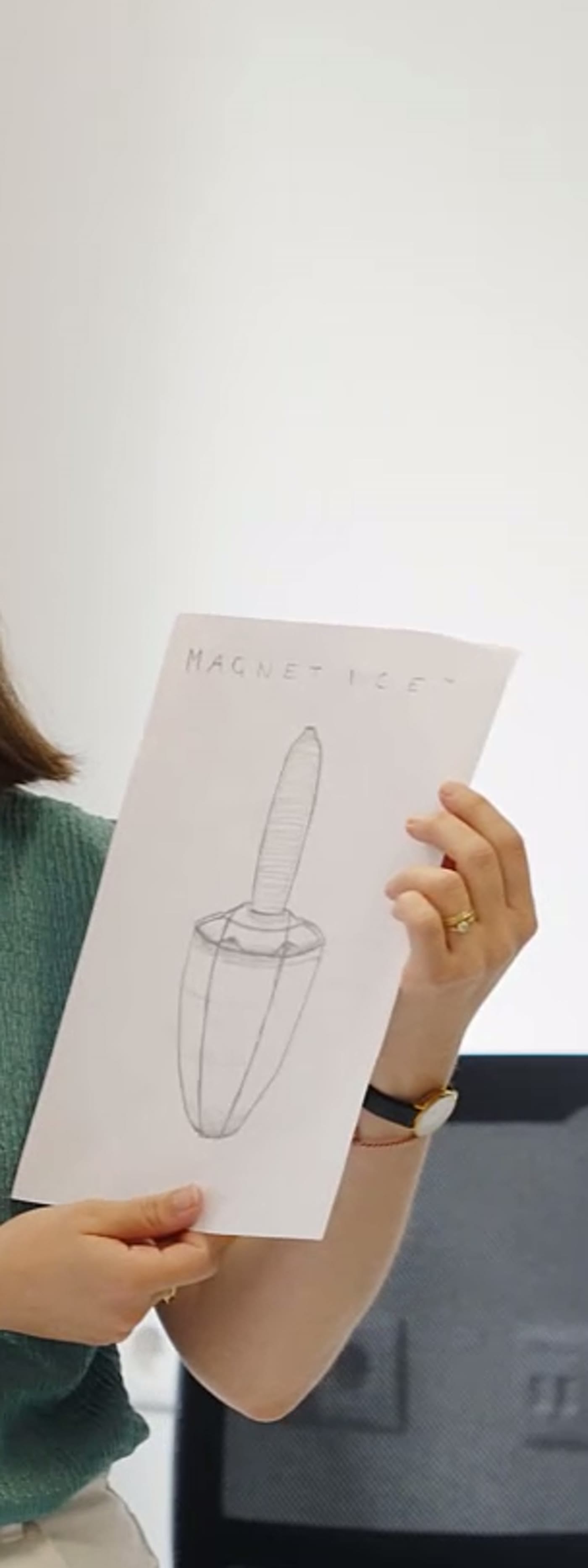 A student holding up her design sketch for a product she invented