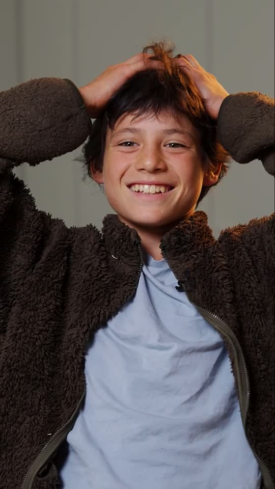 A student pausing mid-thought, hands behind his head, smiling